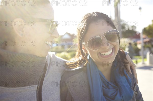 Grinning mixed race sisters hugging outdoors