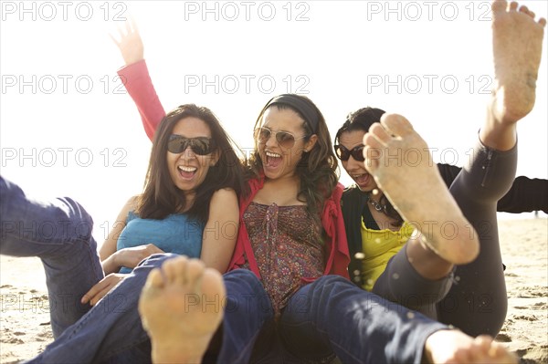 Smiling mixed race sisters playing on beach