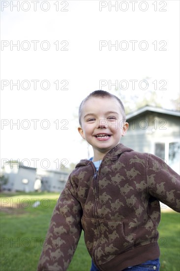 Grinning Caucasian boy playing in yard