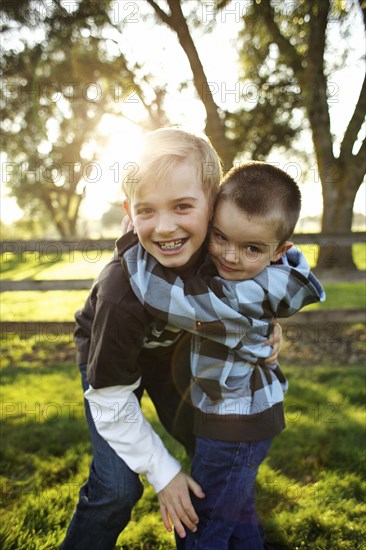 Caucasian brothers hugging outdoors