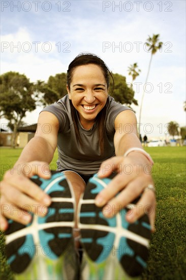 Hispanic woman stretching in park before exercising