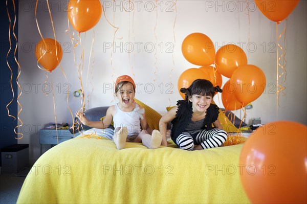 Girls sitting on bed together with balloons