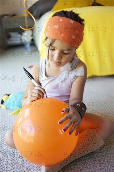 Mixed race girl drawing on balloon