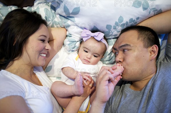 Mother and father laying in bed with baby girl