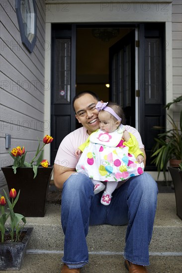 Father sitting on front stoop with baby girl