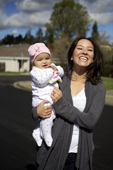 Mixed race mother holding baby girl outdoors