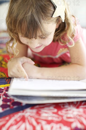 Mixed race girl reading on bed