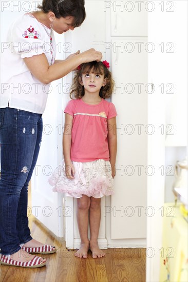 Mother measuring daughter's height