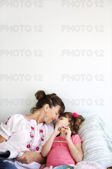 Mother and daughter relaxing on bed