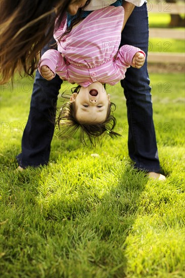 Mother holding toddler daughter upside down