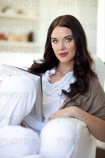 Woman sitting on sofa reading magazine