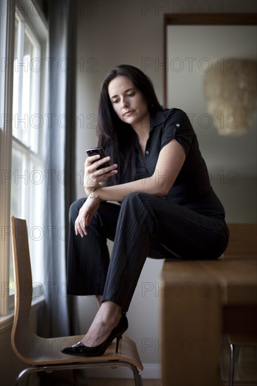 Caucasian businesswoman sitting in table using cell phone