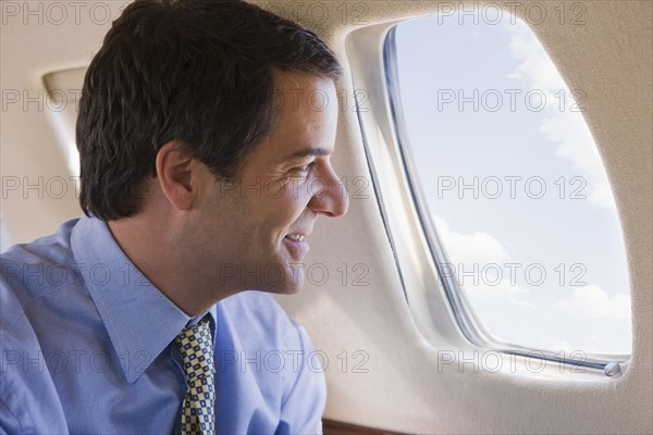 Hispanic businessman looking out airplane window
