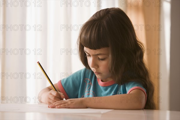 Hispanic girl writing at table