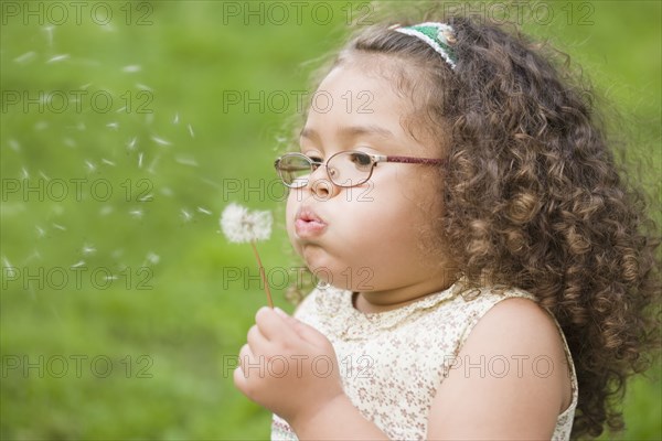 Hispanic girl blowing dandelion