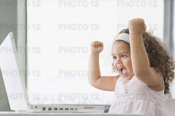 Hispanic girl cheering and using laptop