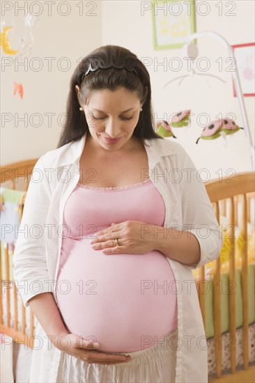 Pregnant Hispanic woman standing in nursery