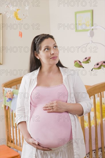Pregnant Hispanic woman standing in nursery