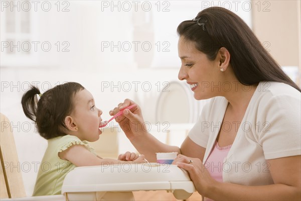 Hispanic mother feeding young daughter