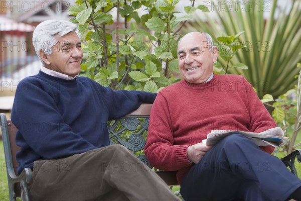 Senior Hispanic friends sitting on park bench