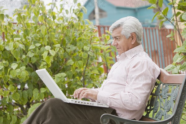 Senior Hispanic man typing on laptop