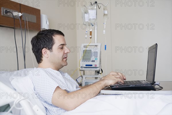 Hispanic man using laptop in hospital