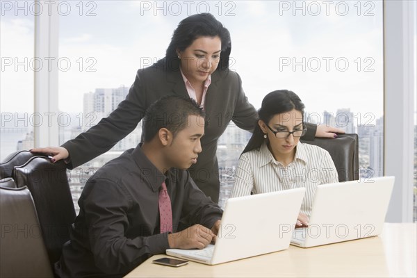 Business people in meeting using laptops