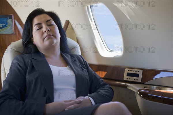 Hispanic businesswoman sleeping on private jet