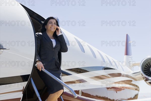 Hispanic businesswoman exiting private jet