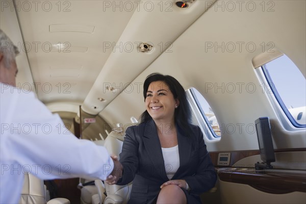 Business people shaking hands on private jet