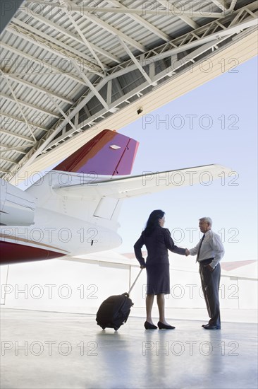 Hispanic business people meeting in airplane hangar