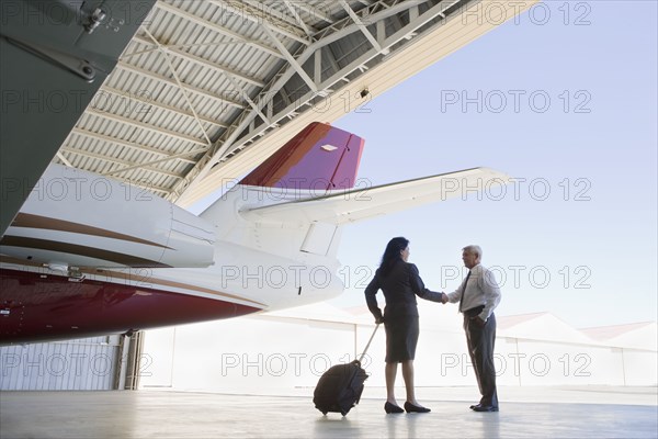 Hispanic business people meeting in airplane hangar