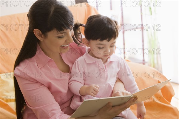 Hispanic mother reading storybook to daughter