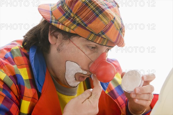 Hispanic man putting on clown makeup