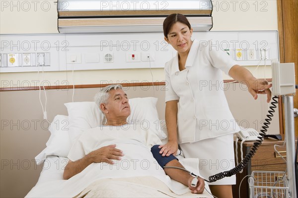 Nurse taking patient's blood pressure in hospital room