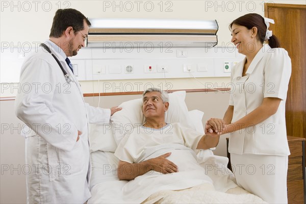 Doctor and nurse talking with patient in hospital room