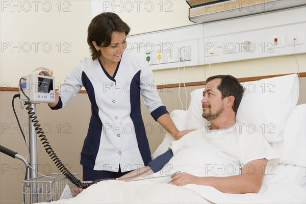 Nurse taking patient's blood pressure in hospital room