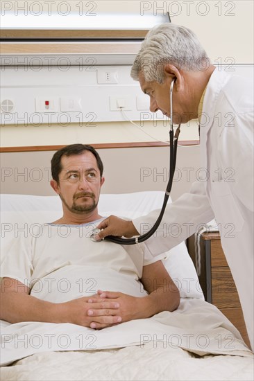 Doctor listening to patient's breathing in hospital room