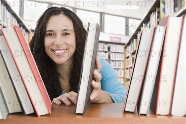 Mixed race woman looking for book in library