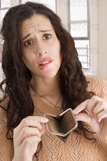 Mixed race woman opening empty coin purse