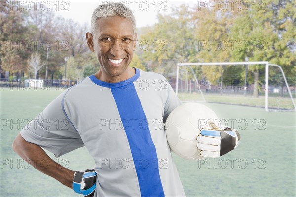 Mixed race man in soccer uniform holding ball