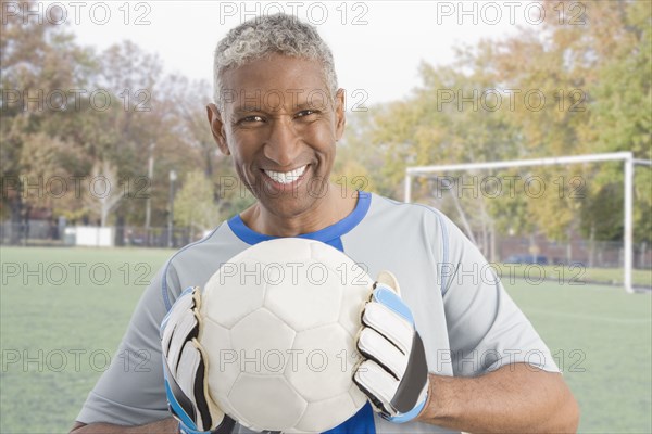 Mixed race man in soccer uniform holding ball