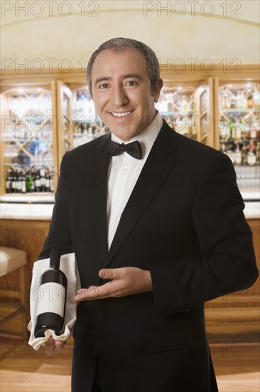 Hispanic sommelier displaying a bottle of wine