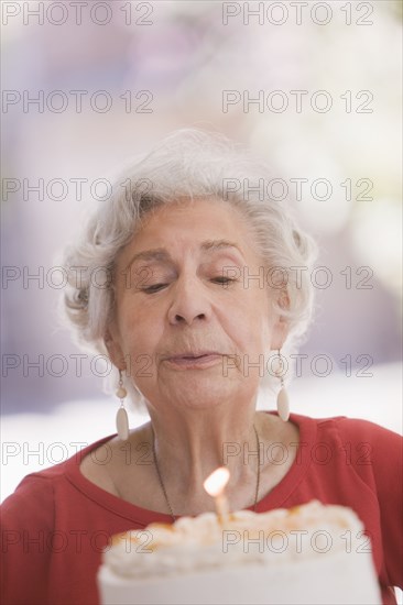 Senior Chilean woman blowing out candle on birthday cake