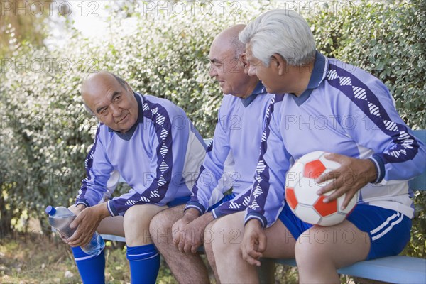 Senior Chilean soccer players sitting on bench