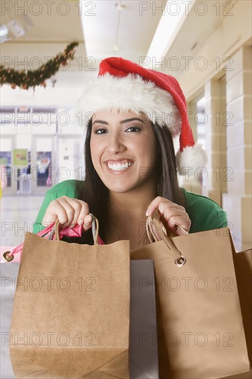 Hispanic woman in santa hat carrying shopping bags
