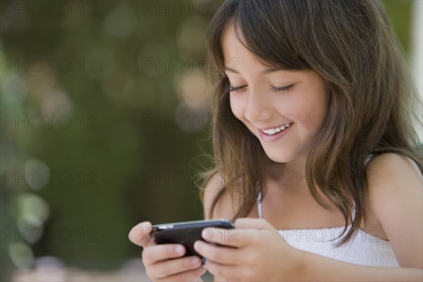 Hispanic girl text messaging on cell phone