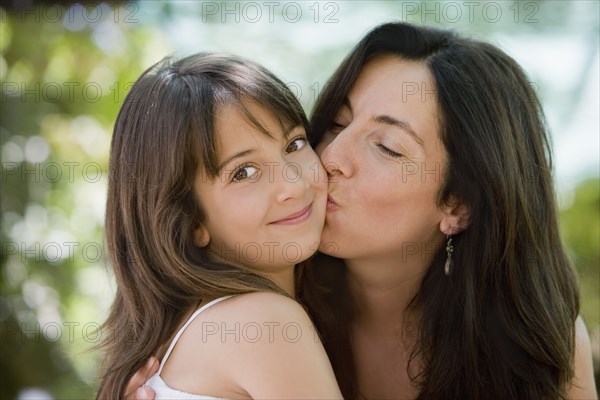 Hispanic mother kissing daughter