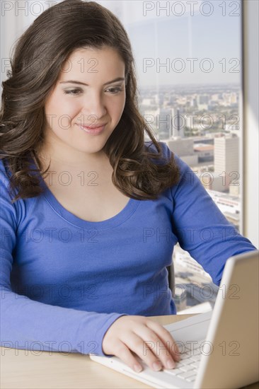 Hispanic teenage girl typing on laptop