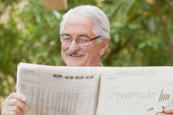 Senior Hispanic man reading financial newspaper